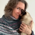 Maria Thomas wearing her Midnight Mountain Capelet and holding her pet Siamese cat.